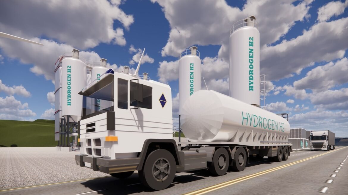 white hydrogen tank truck in front of two hydrogen storage tanks.