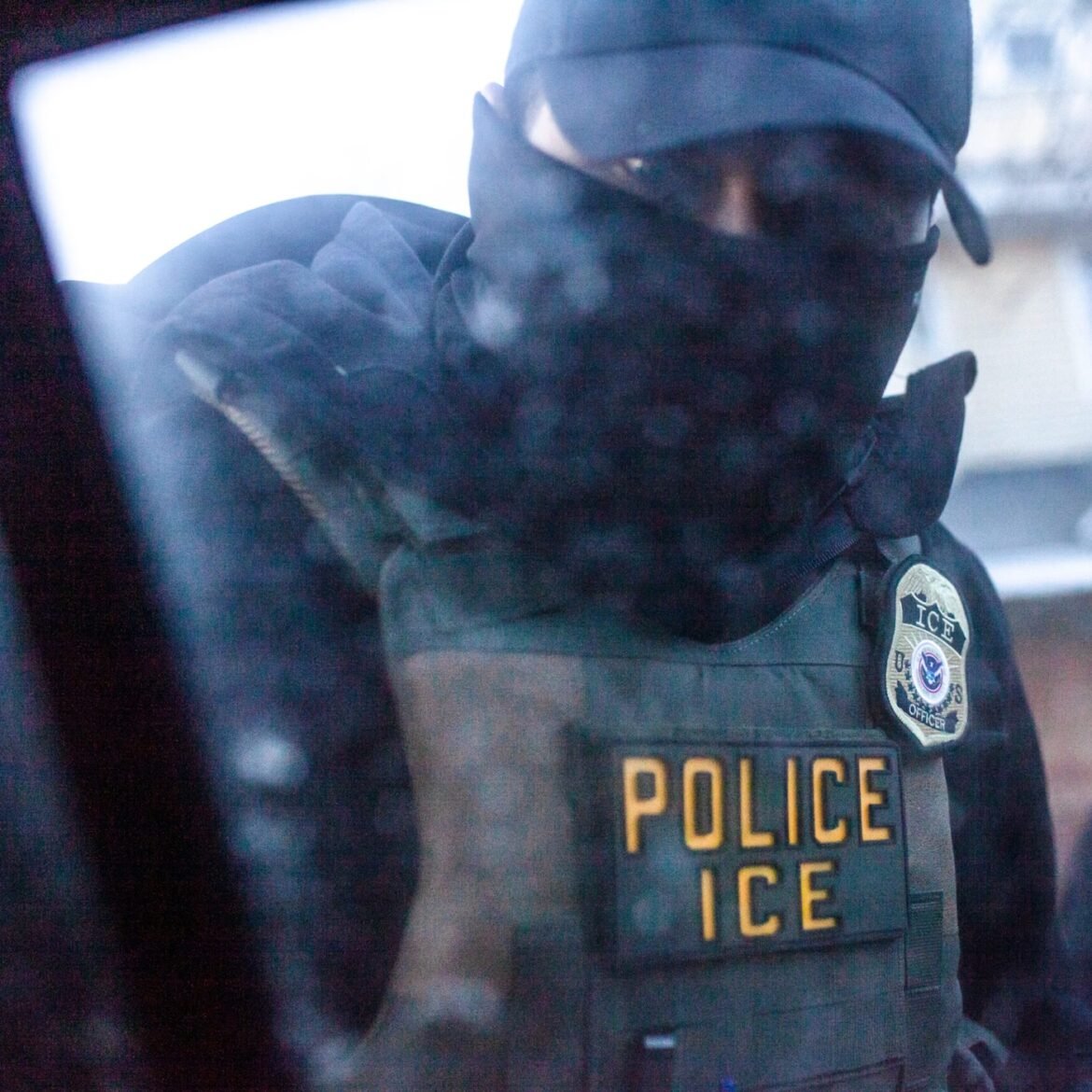 A masked ICE agent knocks on the window and tells observers in Minnesota to stop following ICE vehicles while on an early morning watch Monday, Jan. 12, 2026. (Photo by Nicole Neri/Minnesota Reformer)