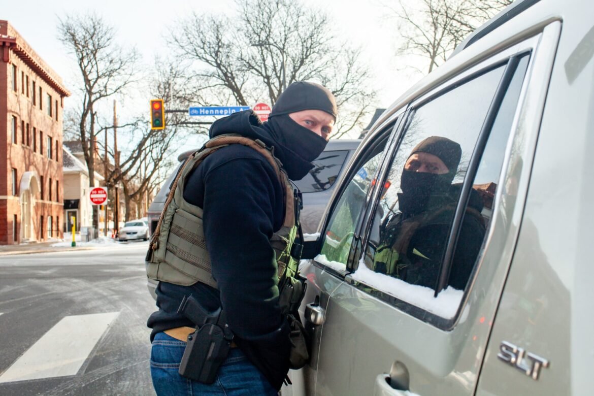 Federal agents block in and stop a woman to ask her for another person’s whereabouts Monday, Jan. 19, 2026 in south Minneapolis. (Photo by Nicole Neri/Minnesota Reformer)