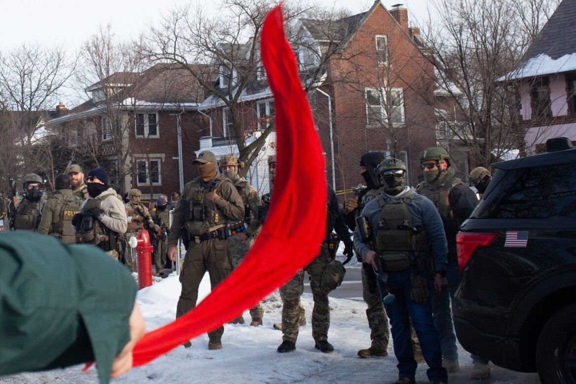 A demonstrator waves a red cloth as hundreds gather after ICE agent Jonathan Ross shot and killed Renee Good through her car window Wednesday, Jan. 7, 2026 near Portland Avenue South and East 34th Street in Minneapolis. (Photo by Nicole Neri/Minnesota Reformer)