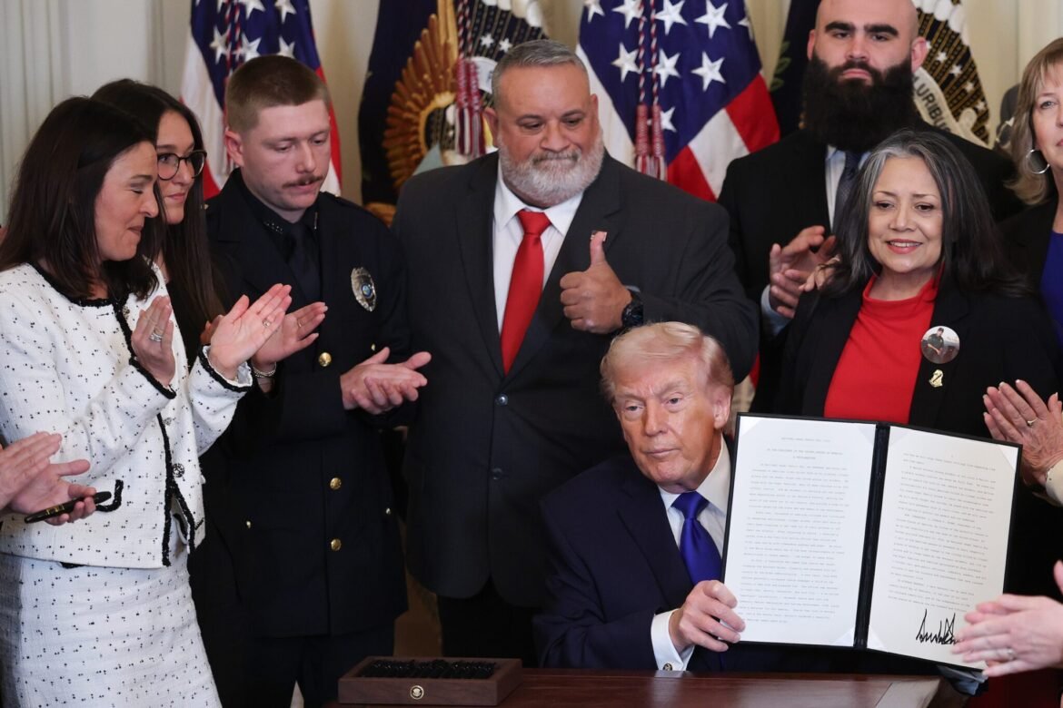 President Donald Trump, surrounded by people who have lost relatives to a crime committed by an immigrant, holds up a proclamation dedicating Feb. 22 as "Angel Family Day" during a &nbsp;ceremony held in the East Room of the White House on Feb. 23, 2026. Photo by Win McNamee/Getty Images)