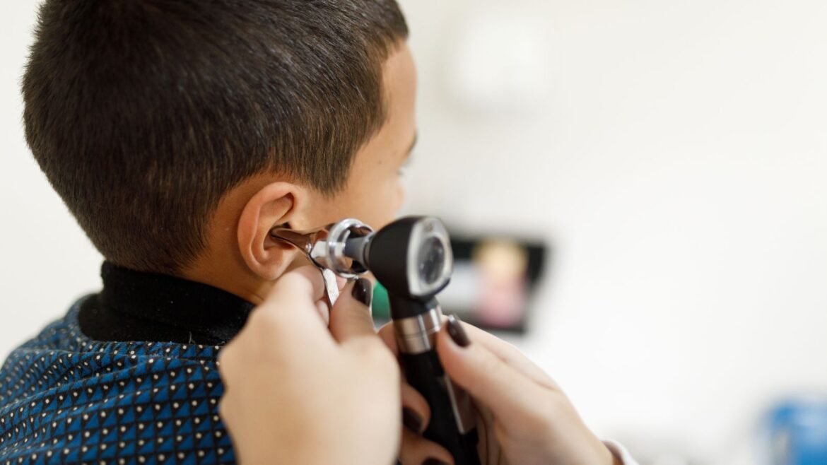 Doctor checking little boy's ears with an otoscope 