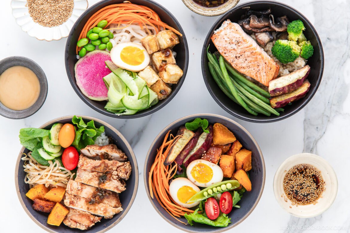 Build-Your-Own Japanese Meal Prep Bowls with rice and varied toppings including salmon, crispy tofu, karaage chicken, and vegetables, served on a marble surface.