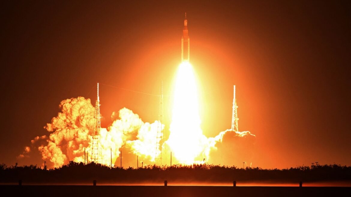 Photo of a stream of orange fire coming from the Artemis I rocket as it launched into space at night