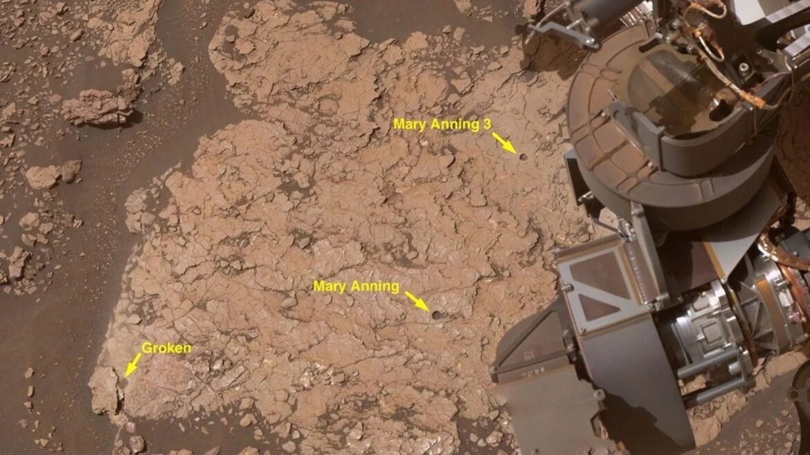 A close up of a reddish brown surface with a metal arm in the right top corner of the image. The image includes yellow arrows and labels of different sites of interest. 