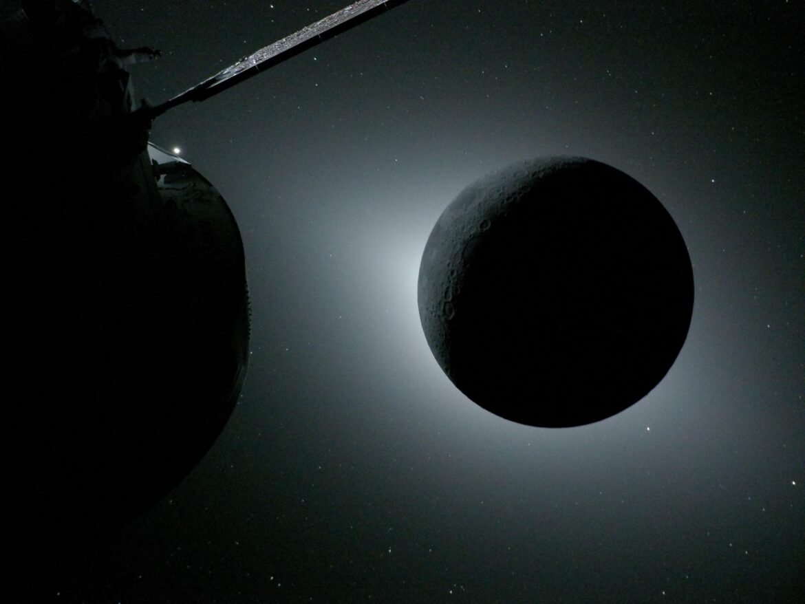 The Moon, backlit by the Sun during a solar eclipse, is photographed by NASA’s Orion spacecraft on April 6, 2026, during the Artemis II mission. Orion is visible in the foreground on the left. Earth is reflecting sunlight at the left edge of the Moon, which is slightly brighter than the rest of the disk. The bright spot visible just below the Moon’s bottom right edge is Saturn. Beyond that, the bright spot at the right edge of the image is Mars.