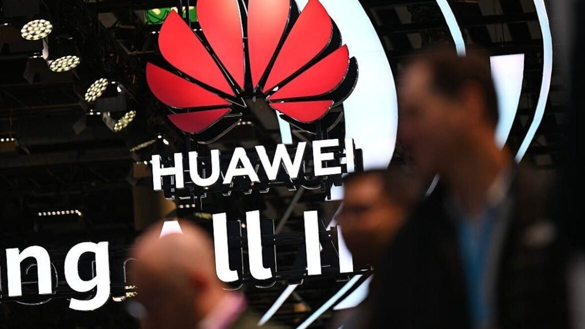 Huawei's logo hangs from the ceiling as several blurry people pass by the camera in the foreground.