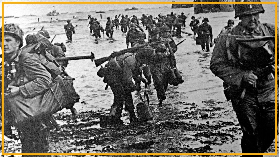 A black and white photo of soldiers in World War II uniforms walking up a beach. 