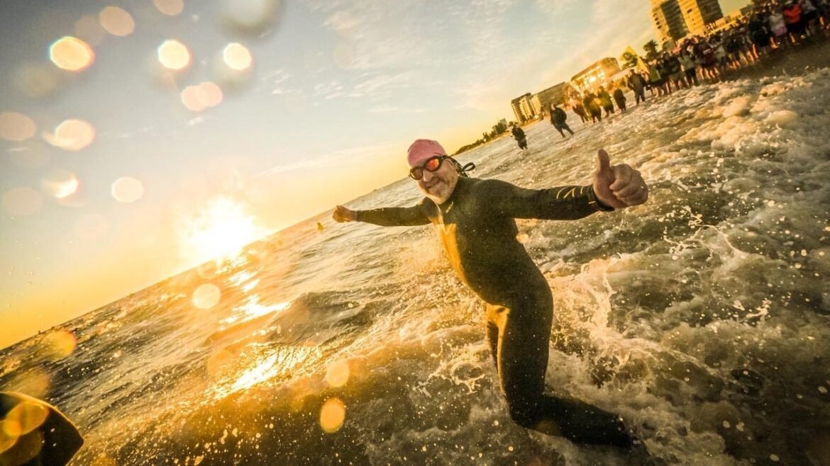 A triathlete runs into the water for an Ironman as the sun rises.