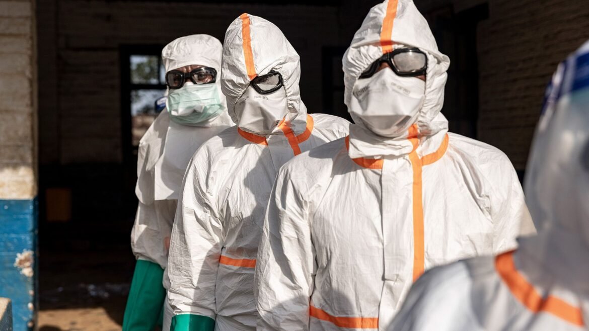 A series of people wearing white clean suits and goggles with masks.