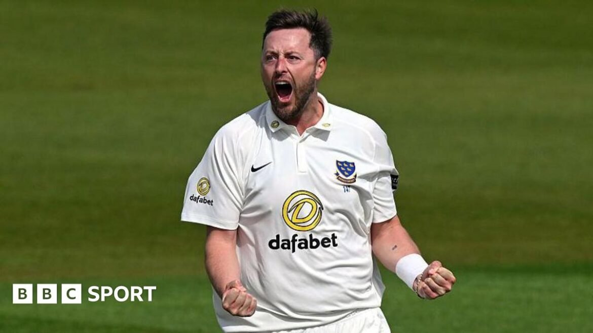 Ollie Robinson, wearing a white Sussex shirt, roars and clenches both of his fists in front of him to celebrate a wicket