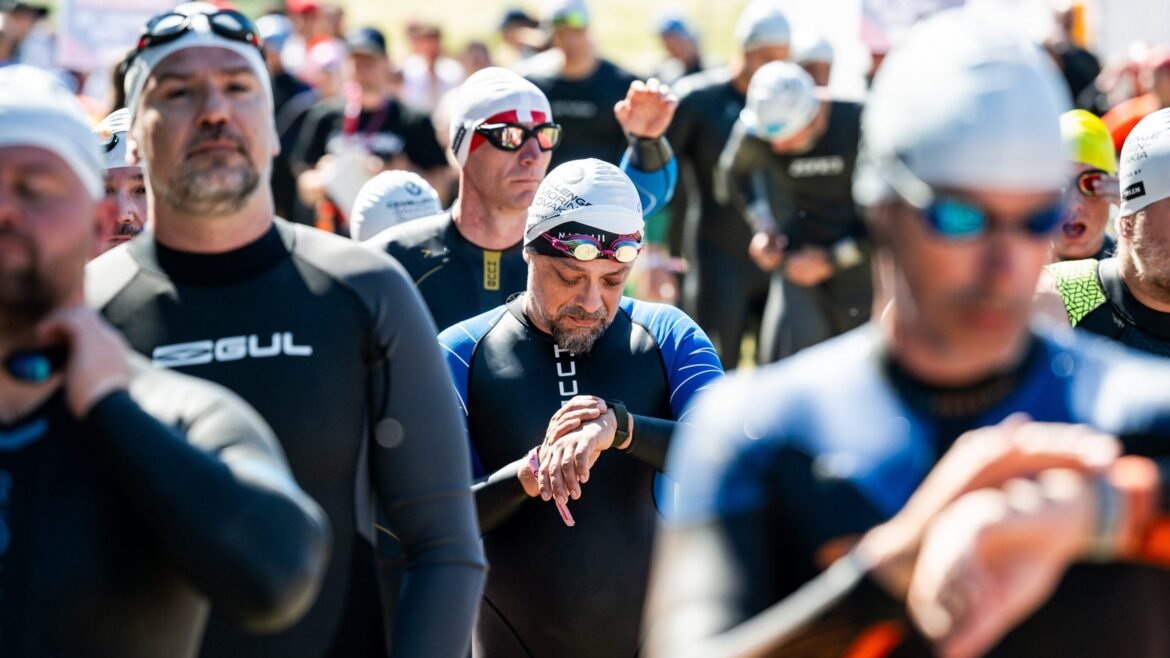 Athletes at the start of a triathlon look down at their watches to set their heart rate zones.