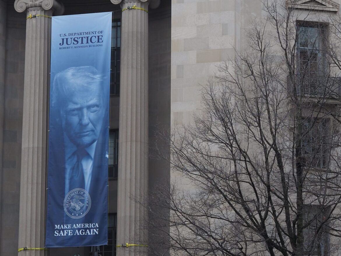 A banner showing President Donald Trump hangs on the Robert F. Kennedy Building of the U.S. Department of Justice on Feb. 20, 2026. (Photo by Shauneen Miranda/States Newsroom)