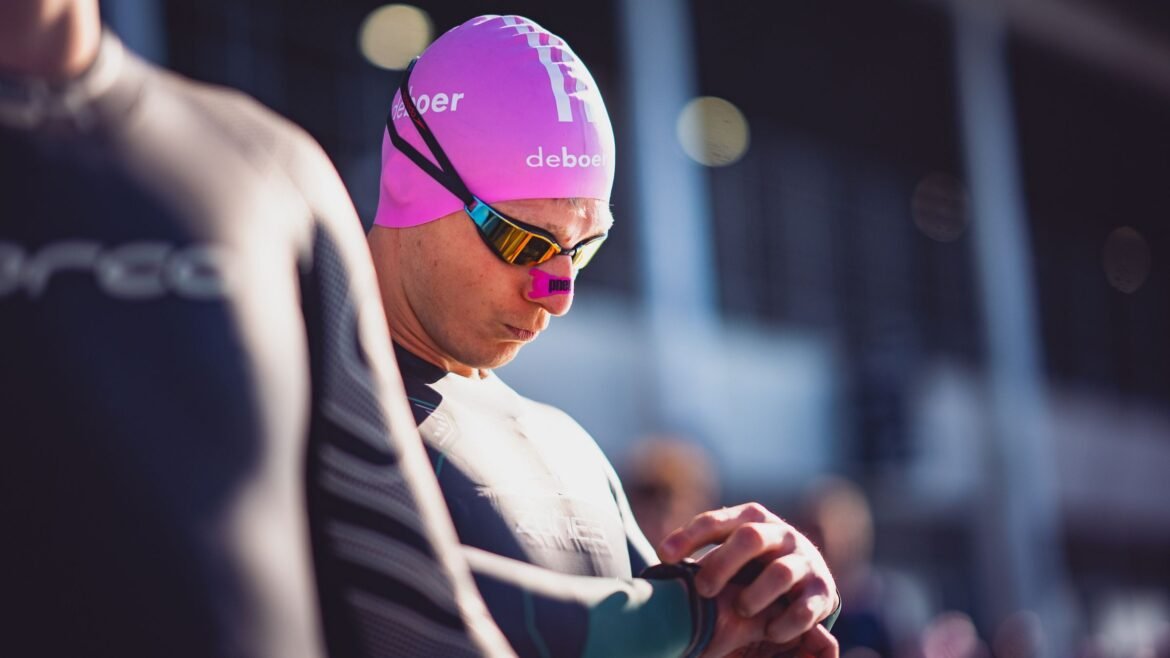 A triathlete looks at their watch, taking its metrics too seriously, and causing the nocebo effect in triathlon training.