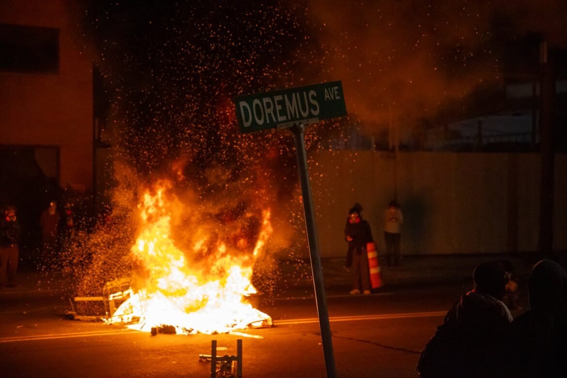 Protestors move around a fire in the middle of Doremus Ave outside Delaney Hall in Newark, NJ on Saturday, May 30, 2026.
