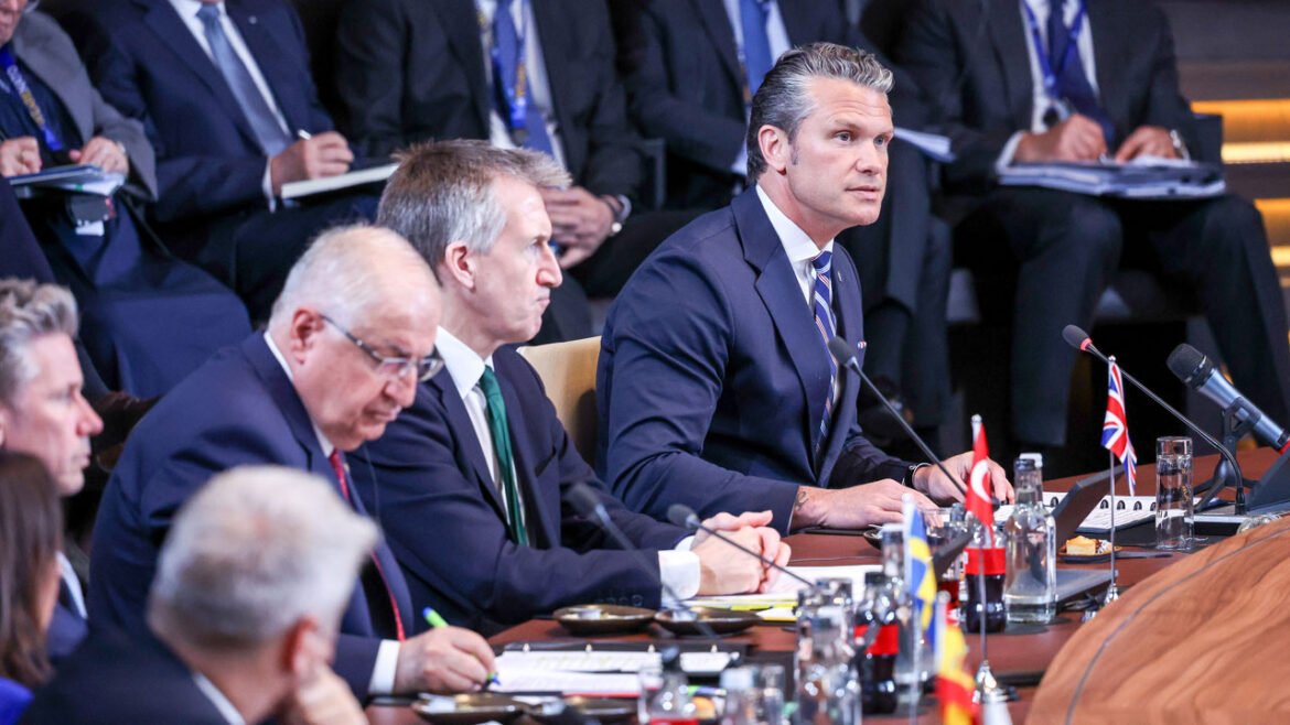 Secretary of War Pete Hegseth speaks while at a table alongside fellow NATO defense ministers.