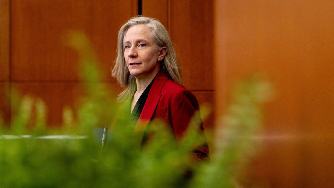 Gov. Abigail Spanberger in red jacket, seen through a row of marijuana plants in the foreground.