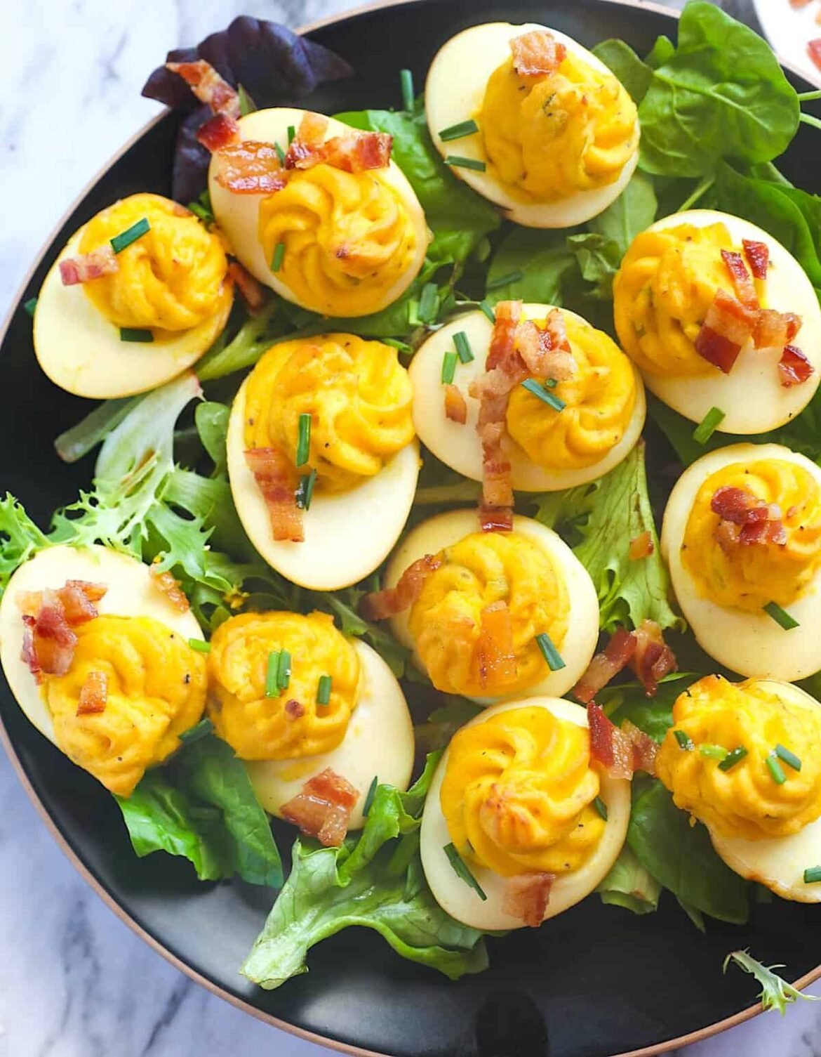 Serving up a platter of smoked deviled eggs topped with bacon for a family picnic.