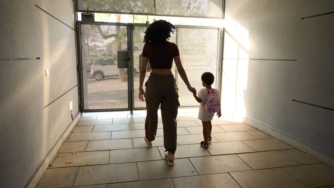 Young black woman leads child toward outside door.