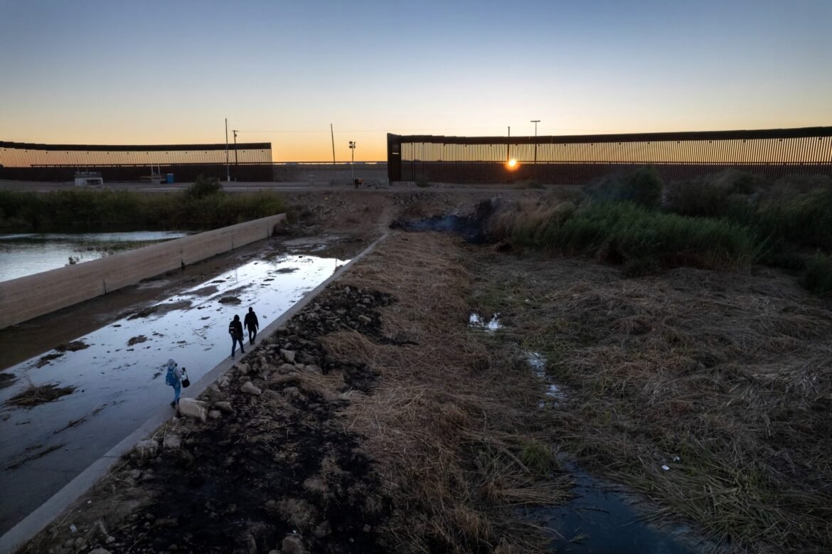 An immigrant family from Haiti walks towards a gap in the U.S.-Mexico border wall near Yuma, Arizona, in December 2021. (Photo by John Moore/Getty Images)