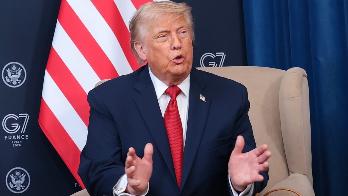 Trump in a dark suit and red tie sits in a beige chair, gesturing with his hands. Behind him are a partial U.S. flag and banners with G7 France 2019 and the U.S. State Department seal.