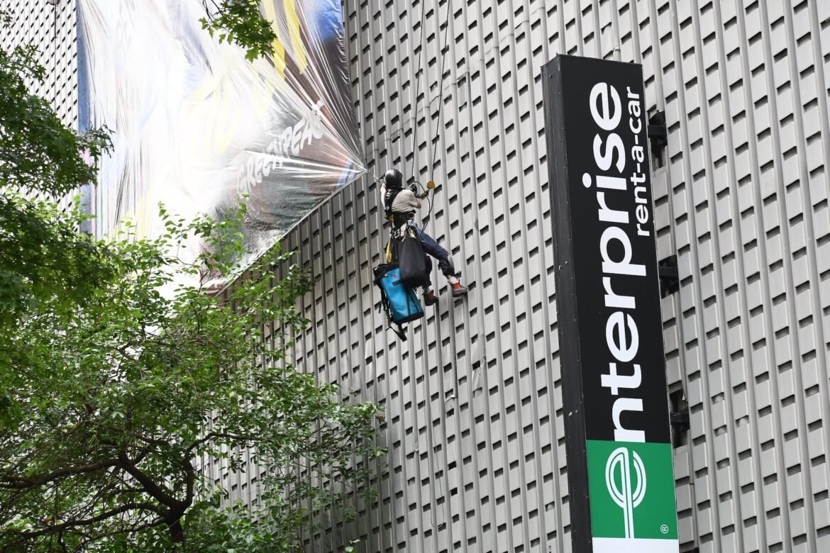Protestors scale a building to hang a massive banner for a Dove men's health protest.