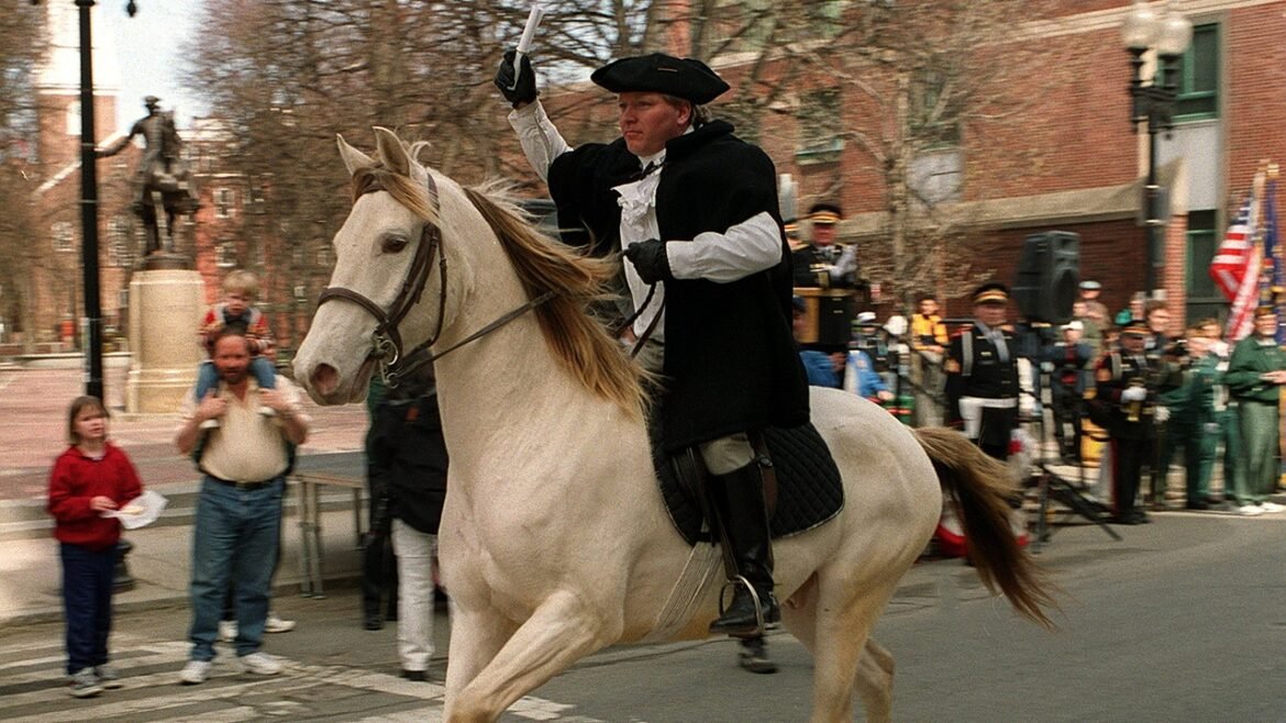 A Paul Revere reenactor rides on a horse