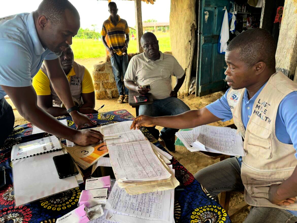 Genesis Whegelee (right, in vest) has been a community health worker for Last Mile Health in Rivercess County, Liberia, since 2018. He visits households to keep an eye on sick children, pregnant moms and anyone with a problem that needs diagnosing.
