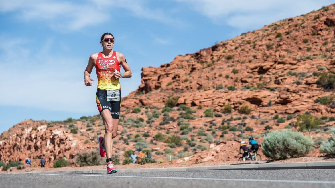 pro triathlete Heather Wurtele runs in the heat of Ironman St. George in front of red rocks outside.