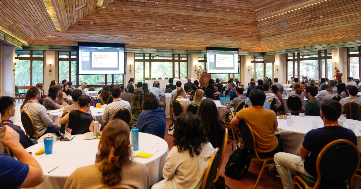 image of people sitting at tables looking at a speaker giving a presentation