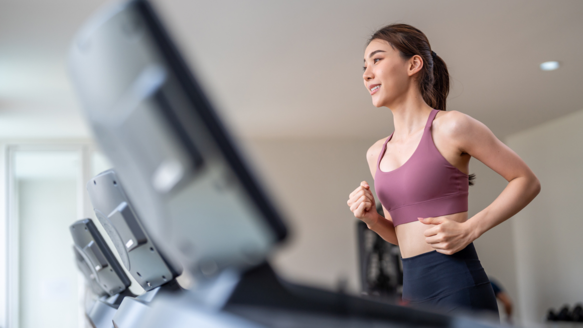 young woman in sports bra runs on a treadmill in the gym