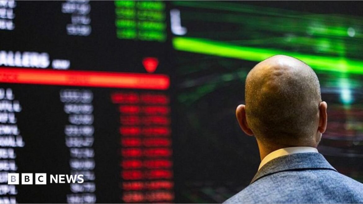 A stock marker trader looks at a large screen