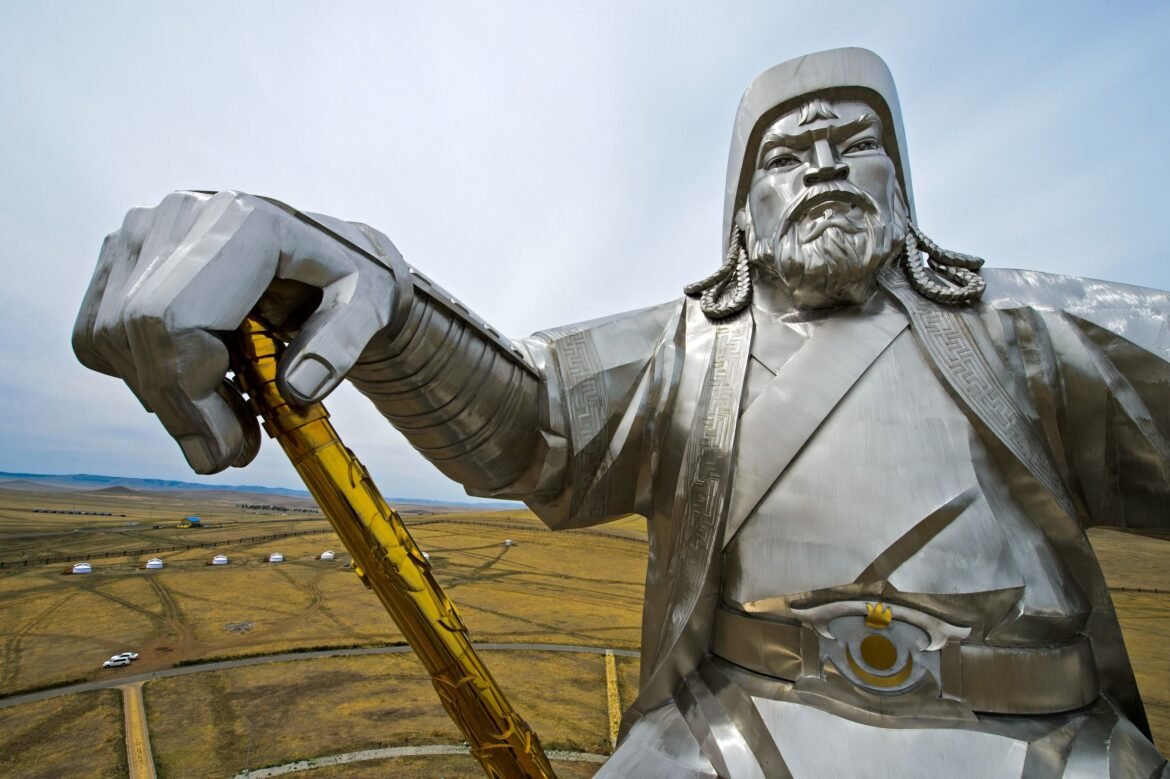 A metal statue of genghis khan with grasslands in background
