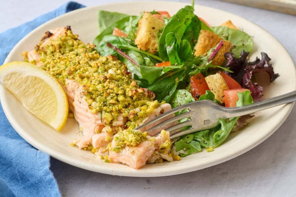 Best pistachio crusted baked salmon filet on a plate with a fork breaking off a piece.