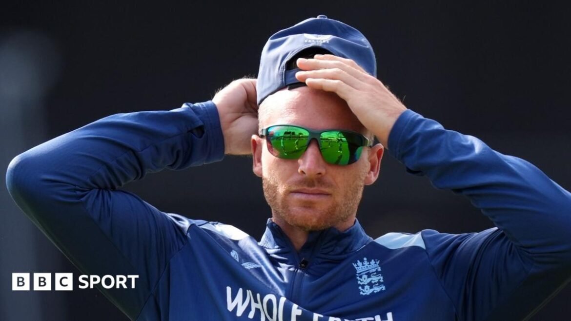 Jos Buttler rubs his head, while wearing sunglasses and a cap