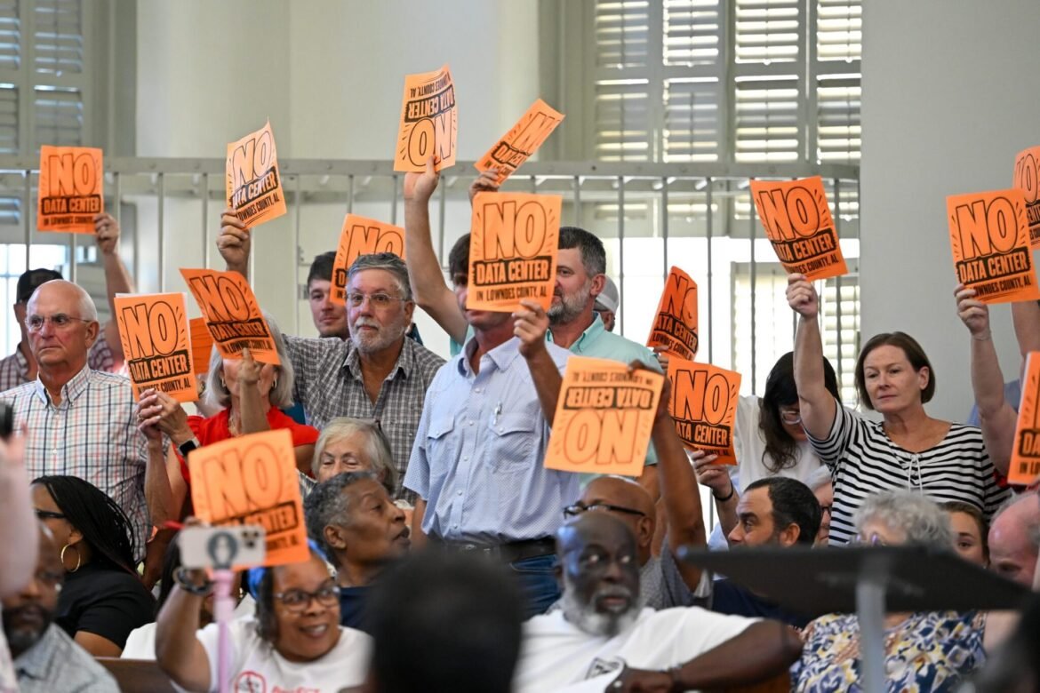 Alabamans hold up signs that read “No Data Center” at a County Commission meeting on Aug. 24, 2026, in Hayneville, Alabama, in the Lowndes County Courthouse. (Anna Barrett/Alabama Reflector)
