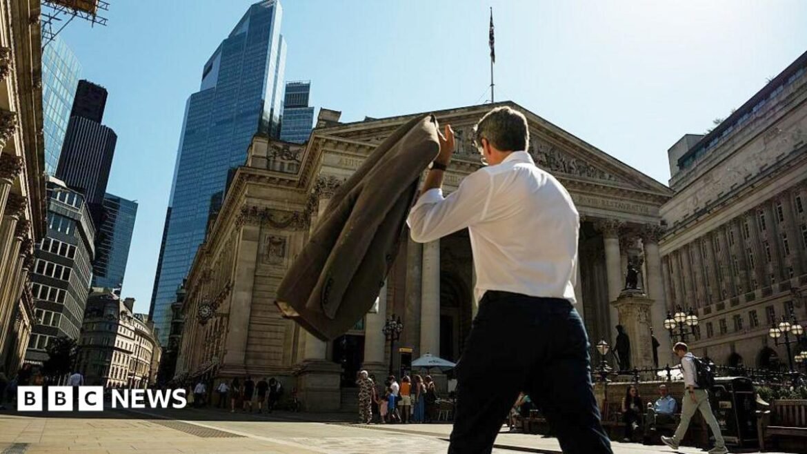 A commuter carries his jacket on a sunny day in the City of London