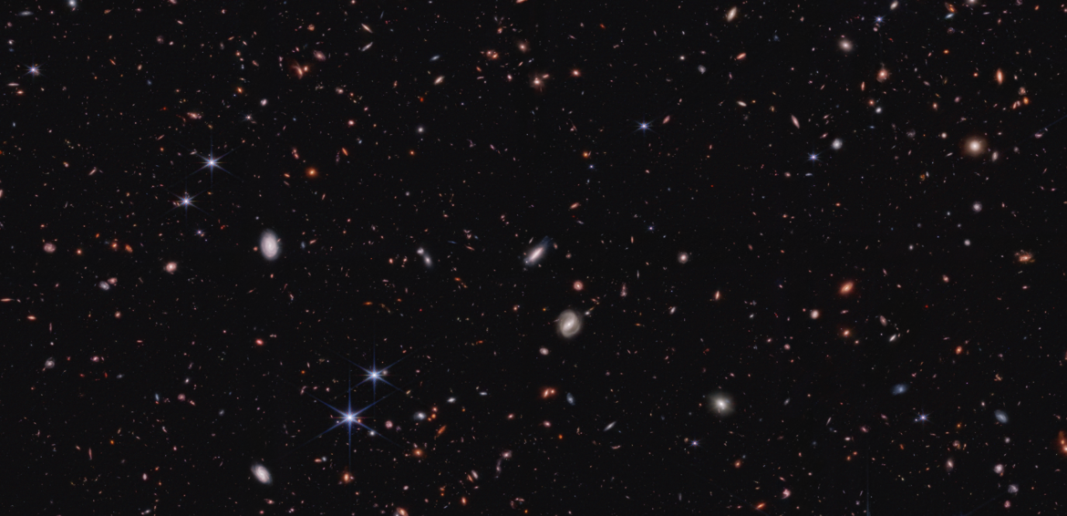 The blackness of space is interrupted by a smattering of tiny, colorful blobs