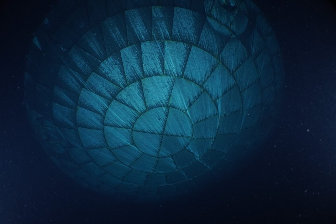 The Orion spacecraft's heat shield dominates this underwater photo. Due to the water, the heat shield appears to be teal-colored.