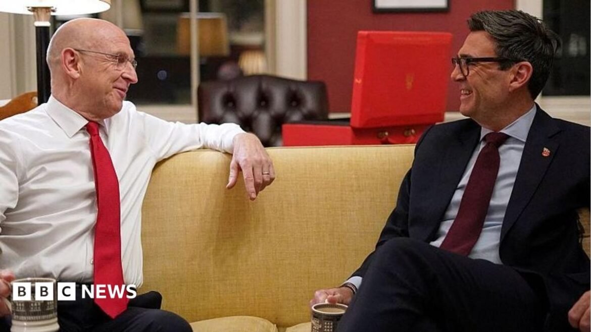 Chancellor of the Exchequer John Healey ahead of the UK budget at 11 Downing Street in London on October 26, 2026 sitting on a sofa smiling and talking to Prime Minister Andy Burnham. Both men are holding cups of tea.